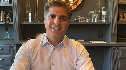 Chris sitting at his desk, smiling at the camera